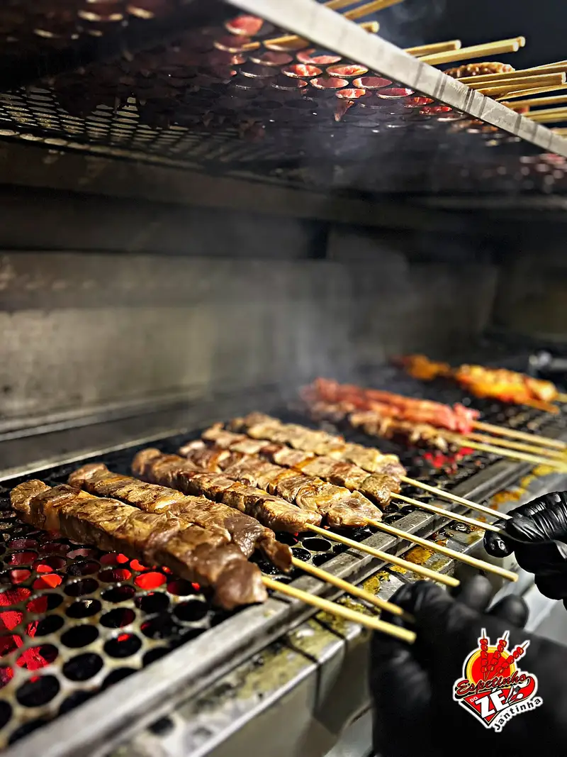 Espetinhos de carne na brasa da churrasqueira, com o carvão aceso